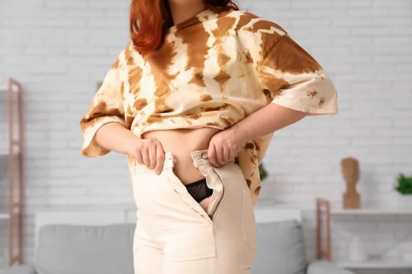 Image of woman trying to do her trousers up after pregnancy weight gain Leicestershire
